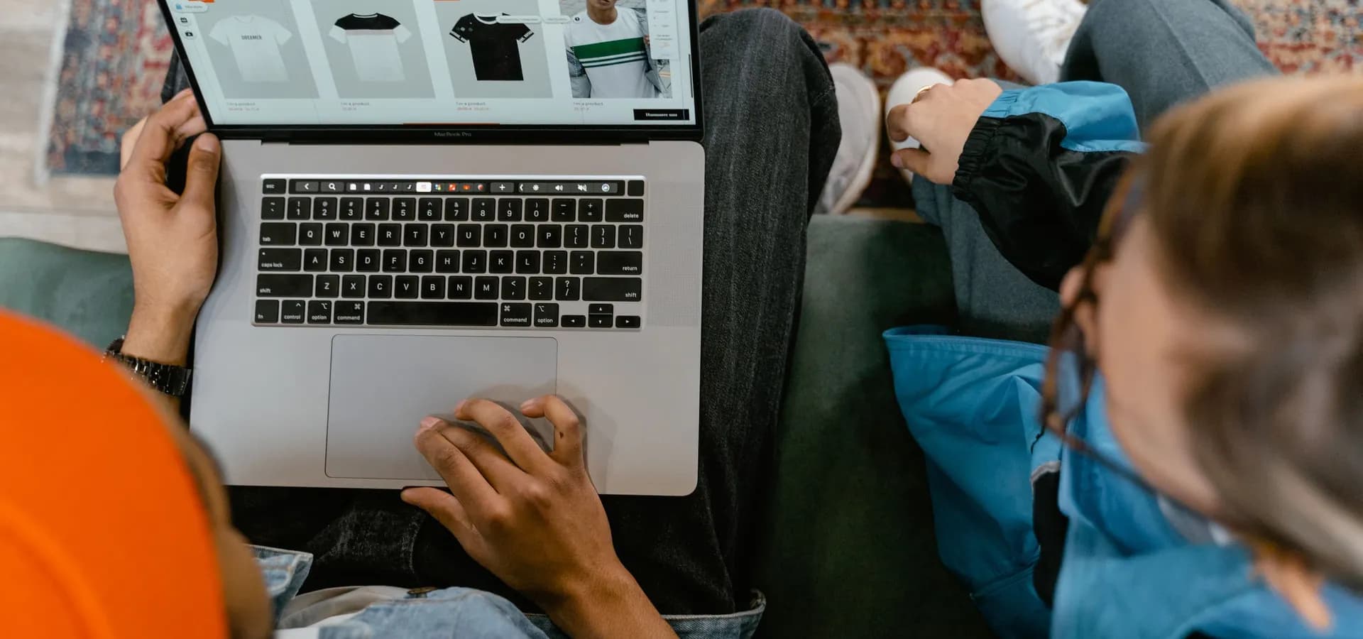 Dvoje ljudi zajedno pregledava internetsku trgovinu odjećom na prijenosnom računalu dok sjede na kauču.