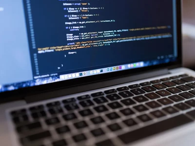 računalo s prikazanim kodom web-stranice na stolu u uredu
