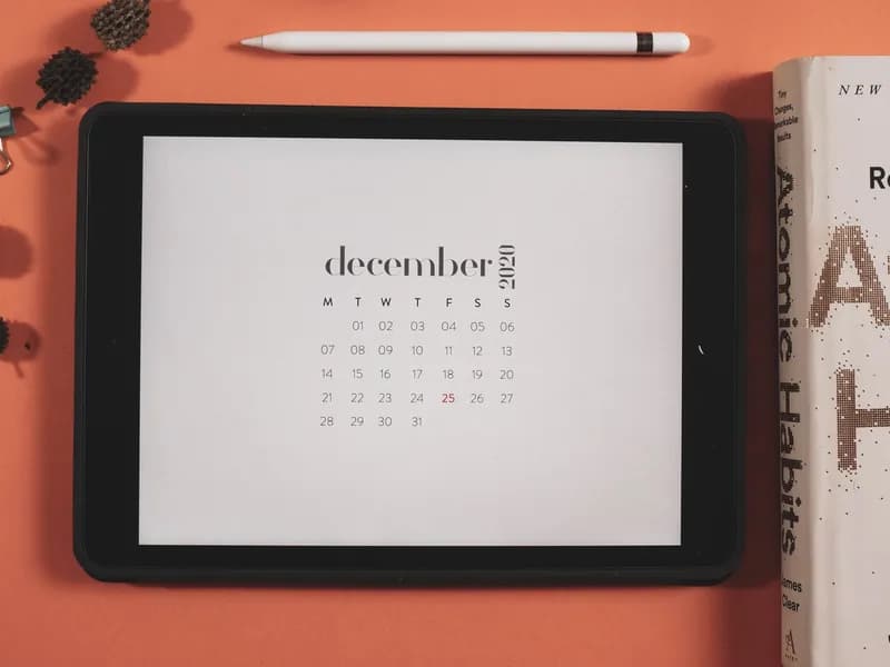Tablet s prikazom digitalnog kalendara na urednom uredskom stolu