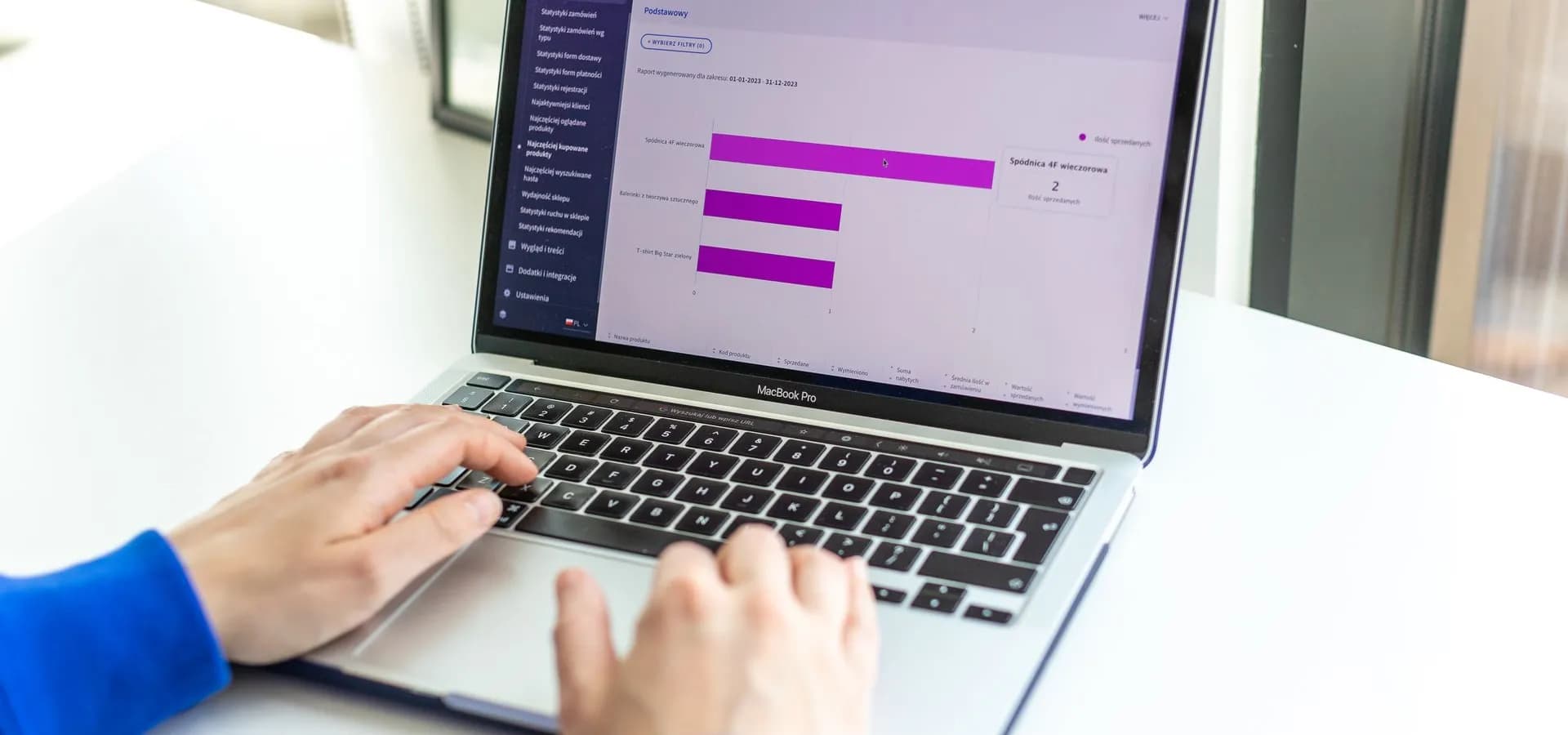 Osoba radi na laptopu s prikazom webshop analitike i poslovnih podataka.