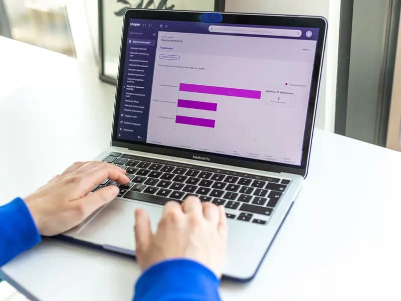 Osoba radi na laptopu s prikazom webshop analitike i poslovnih podataka.