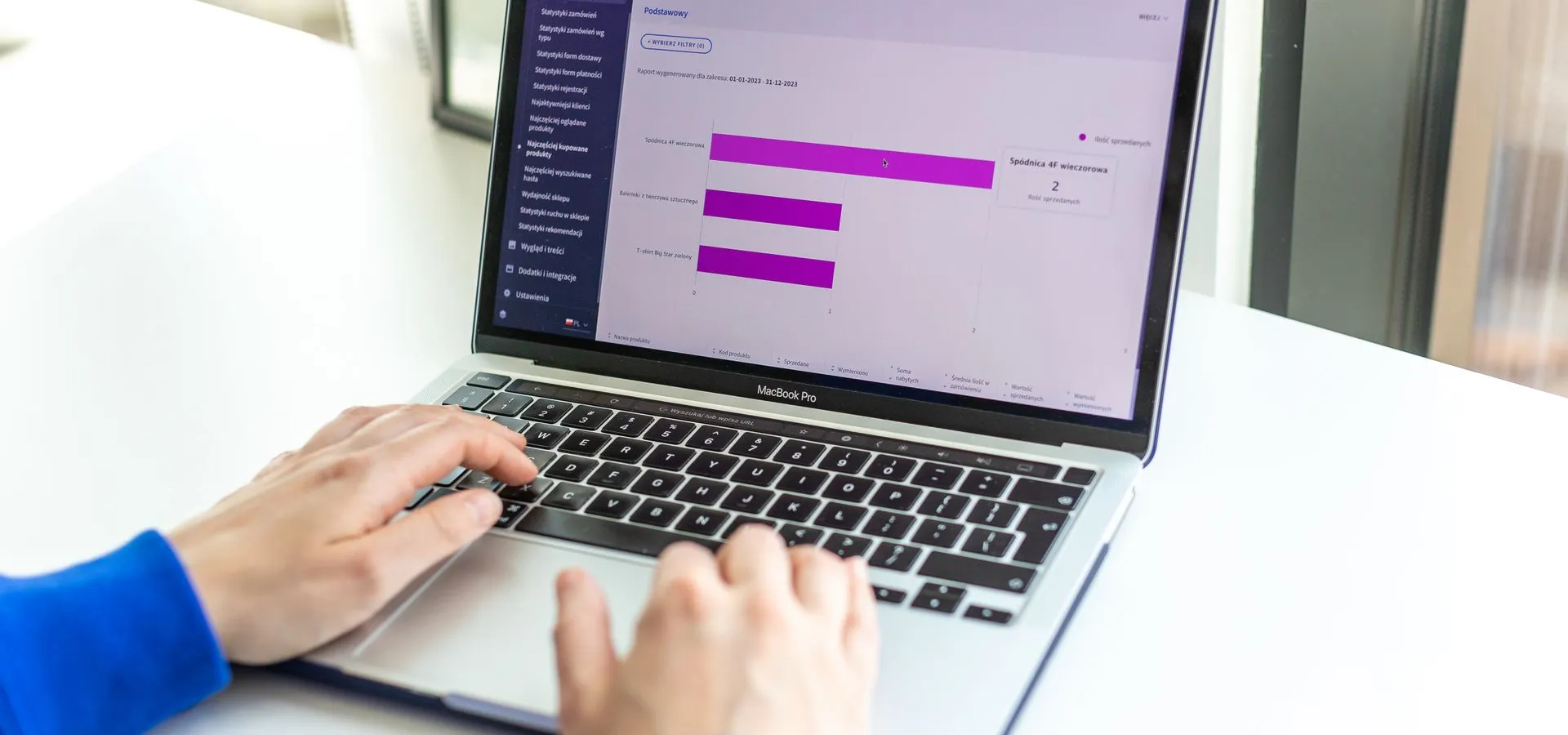 Osoba radi na laptopu s prikazom webshop analitike i poslovnih podataka.