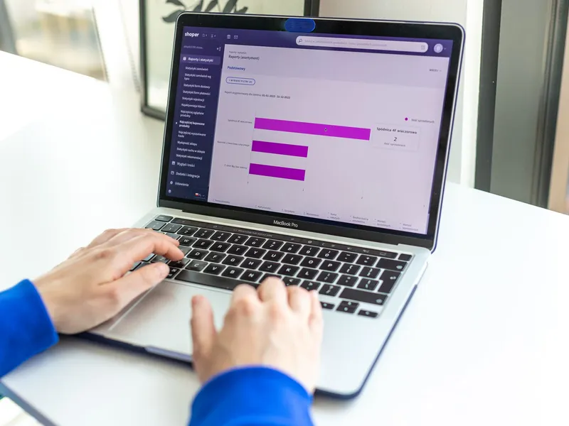Osoba radi na laptopu s prikazom webshop analitike i poslovnih podataka.
