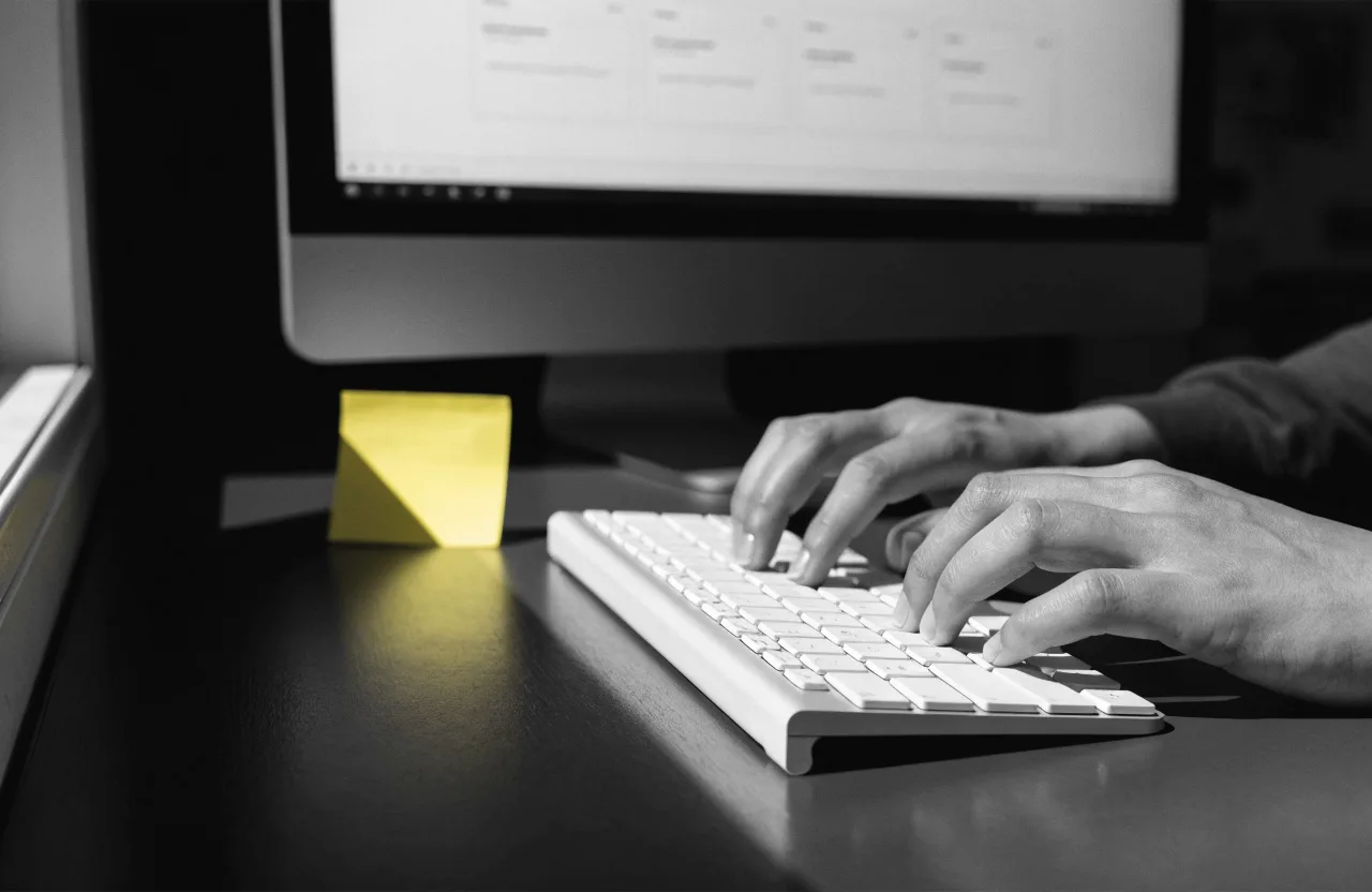 Ruke na tipkovnici ispred monitora s rasporedom web stranice